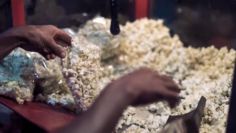 A-Pair-Of-Hand-Suffling-PopCorns-In-a-Table-preparing-for-packing-them