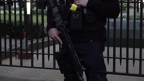 UK-October-2018---People-walk-past-a-police-officer-resting-his-hand-on-the-handle-of-an-assault-rifle-as-he-stands-guard-outside-the-Saudi-Arabian-embassy-in-London-at-dusk