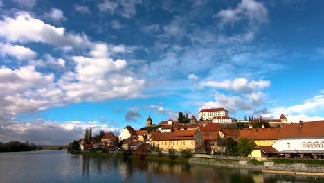 Casco-Antiguo-De-Ptuj,-Eslovenia,-Vista-Desde-El-Puente-Peatonal-A-Través-Del-Río-Drava-En-El-Casco-Antiguo-Y-El-Castillo-Que-Domina-El-Paisaje-Urbano