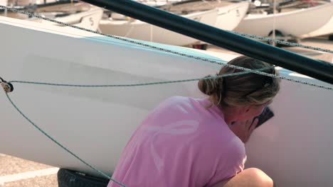 Una-Joven-Marinera-Fregando-Y-Limpiando-El-Casco-De-Su-Velero-A-Cámara-Lenta-Después-De-Navegar-En-Una-Regata