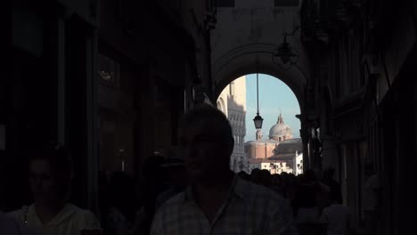 Tourists-walk-through-a-building-with-beautiful-arch-architecture-in-Venice,-Italy