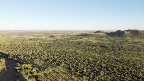 Toma-Aérea-Inversa-Que-Revela-Una-Colina-Con-Ciclistas-Con-árboles-Verdes-Y-Campo-Verde