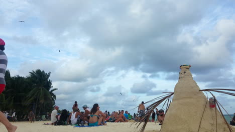 Playa-Llena-De-Gente-En-México-En-Un-Día-Soleado-Con-Un-Muñeco-De-Nieve-Hecho-De-Arena.