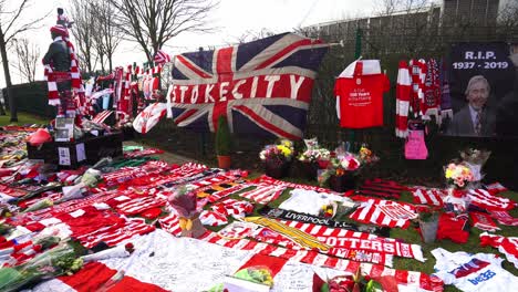 People-pay-their-respects-at-the-Gordon-Banks-statue-by-the-Stoke-City-stadium,-people-signing-shirts,-scarves,-flags-and-the-book-of-remembrance