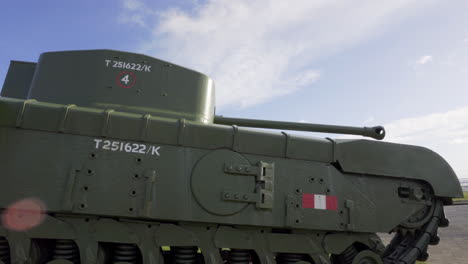 Churchill-tank-memorial-at-sea-front-in-Carrickfergus,-green-tank,-blue-sky-with-some-cloud,-lens-flare-in-corner