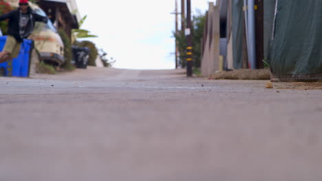 Vista-En-ángulo-Bajo-De-Un-Adolescente-Montando-En-Patineta-Y-Haciendo-Slalom-De-Un-Lado-A-Otro-Cuesta-Abajo-En-Una-Carretera-Estrecha-Y-Hace-Un-Gran-Deslizamiento-En-La-Patineta-Para-Reducir-La-Velocidad