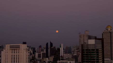 Timelapse-De-La-Tarde-A-La-Noche-De-La-Luna-Crepuscular-Roja-Que-Se-Eleva-Detrás-Del-Hotel-Pullman-Bangkok-G,-Bang-Rak,-Bangkok