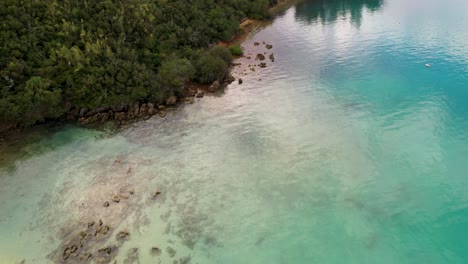 Luftaufnahme-Einer-Frau-Mit-Stand-Up-Paddle-An-Der-Küste-Im-Klaren-Türkisfarbenen-Wasser-Einer-Tropischen-Insel