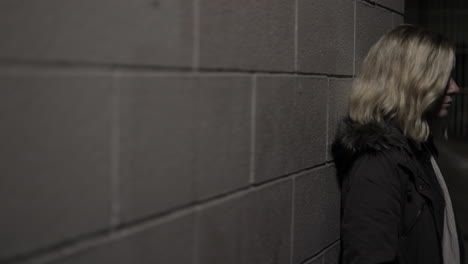 Girl-leans-against-a-wall-in-an-alley-at-night