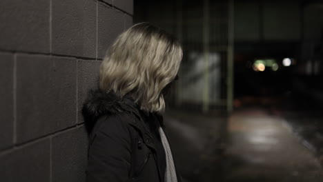 Girl-leans-against-a-wall-in-an-alley-at-night