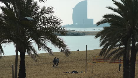 Mujeres-Caminando-Por-Un-Campo-De-Voleibol-De-Playa-En-La-Platja-De-La-Barceloneta,-La-Playa-De-La-Barceloneta