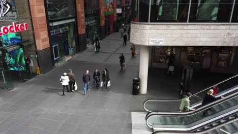 High-angle-perspective-view-down-to-shoppers-in-slow-motion-in-busy-city-shopping-mall,-retail-district