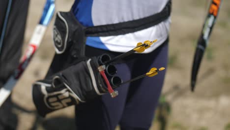 Close-up-of-a-hip-quiver-holding-arrows-as-a-hand-reaches-down-and-grabs-arrows-for-archery-in-Paphos-City,-Cyprus