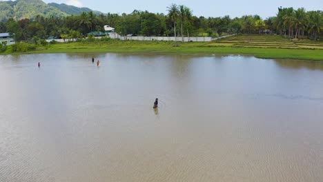 Vista-Aérea-A-Través-De-Un-Grupo-De-Hombres-Ajustando-Redes-En-Agua-De-Laguna-Tropical