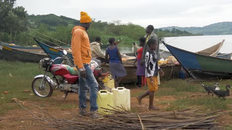 Eine-Gruppe-Afrikaner-Tauscht-Fisch,-Während-Sie-An-Traditionellen-Fischerkanus-Am-Ufer-Des-Lake-Victoria-Stehen