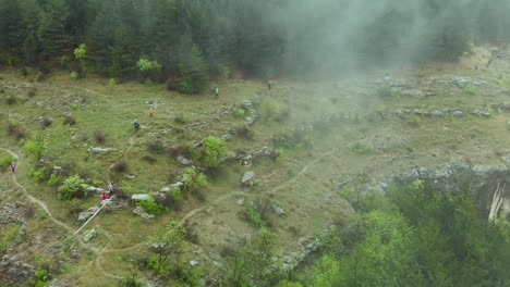 Panorámica-Aérea,-Corredores-De-Maratón-Trotan-En-La-Ladera-Del-Bosque-Búlgaro-Brumoso