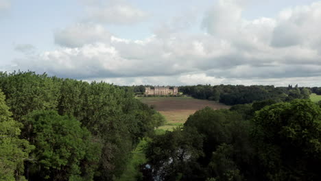 Revelación-Aérea-De-Harewood-House,-Una-Casa-De-Campo-En-El-Oeste-De-Yorkshire,-A-Través-De-Las-Copas-De-Los-árboles