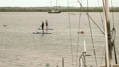 Imágenes-Que-Muestran-A-Dos-Hombres-Practicando-Surf-De-Remo-A-Lo-Largo-Del-Encuadre,-Esto-Está-Filmado-En-Heybridge-Basin-En-Essex