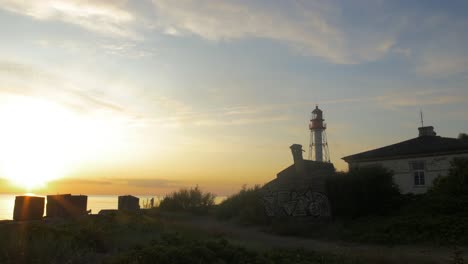 Beautiful-view-of-the-Pape-Lighthouse-on-a-calm-summer-evening-with-slow-moving-clouds-before-the-sunset,-wide-shot