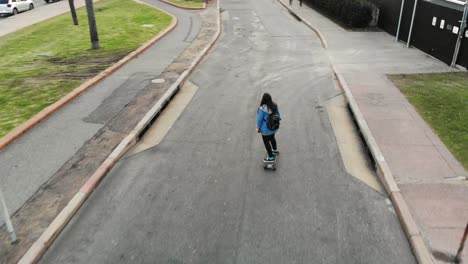 Weiße-Frau,-Die-Auf-Longboard-Die-Straße-Hinunter-In-Montevideo-Uruguay-Skatet