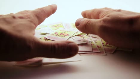 Man's-Hands-Push-One-Time-Bus-Tickets-Into-One-Pile