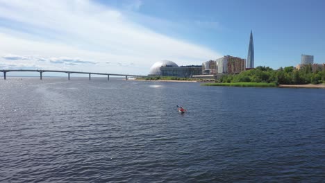 Aerial-Drone-tracking-Shot-of-two-people-riding-a-kayak-under-the-Western-High-Speed-Diameter-bridge,-Gulf-of-Finland-in-Saint-Petersburg,-Russia