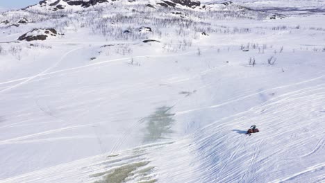 Aerial-view-of-group-of-people-on-snowmobiles-in-snowy-mountain-landscape