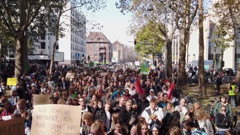 Gran-Multitud-De-Estudiantes,-Adolescentes-Y-Otros-Manifestantes-Marchan-Por-Un-Bulevar-Con-árboles,-Para-Exigir-Una-Acción-Política-Contra-El-Calentamiento-Global