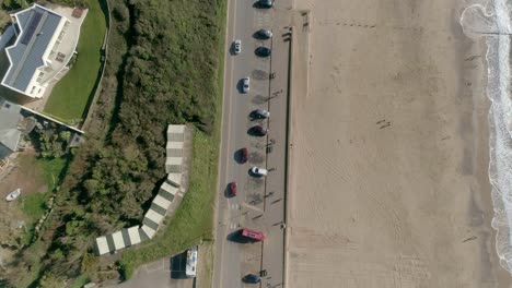 Antena-De-Arriba-Hacia-Abajo-Sobre-Una-Playa-De-Arena-Conectada-Por-Una-Carretera-Costera-Y-Un-Aparcamiento