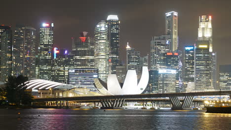 Singapore---Circa-time-lapse-zoom-out-shot-of-famous-Singapore-Marina-sands-bay-with-illuminated-theatre,-sky-scraper-silhouette-and-busy-highway-bridge-in-foreground,-night-time