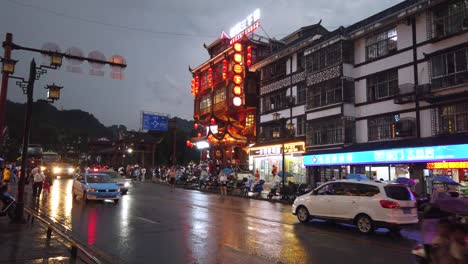 Wulingyuan,-China---Agosto-De-2019:-Vida-Bulliciosa-Con-Automóviles,-Tráfico-Y-Luces-En-Edificios-Iluminados-Por-La-Noche-En-Una-Concurrida-Calle-Principal-De-La-Ciudad-Al-Atardecer