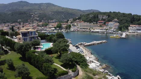 Aerial-view-panning-across-Kassiopi-harbour-entrance,-bright-sunny-day-Corfu-island-Greece