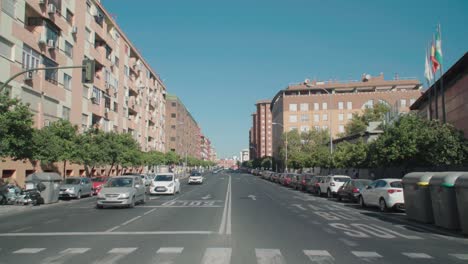 Cars-and-bus-driving-past-camera-on-city-street-in-Seville,-Spain