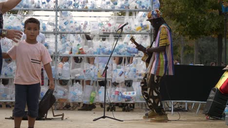 Gitarrenmusiker-Mit-Dreadlocks-Spielt-Während-Des-Jährlichen-Festivals-Von-La-Merce-In-Der-Nähe-Einer-Wand-Aus-Recycelten-Plastikflaschen