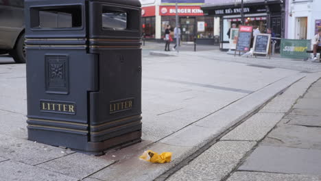 La-Basura-No-Se-Tira-Correctamente-En-El-Contenedor-De-Basura-Público-Y-La-Gente-Ignora-El-Pase-Para-Caminar,-Plano-Medio.