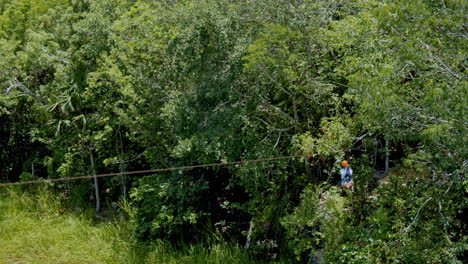 Foto-Lateral-De-Una-Chica-Haciendo-Tirolesa-Sobre-El-Estanque-En-Medio-Del-Bosque,-Cancùn,-México