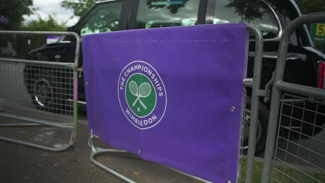 Wimbledon-2019:-Blick-Auf-Den-Straßenzaun-Mit-Dem-Wimbledon-Logo-Darauf,-Mit-Einem-Schwarzen-Taxi-Im-Hintergrund