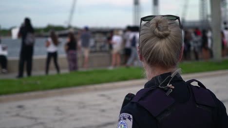 White-female-police-officer-looking-at-crowd-of-Black-Lives-Matter-protestors,-close-up