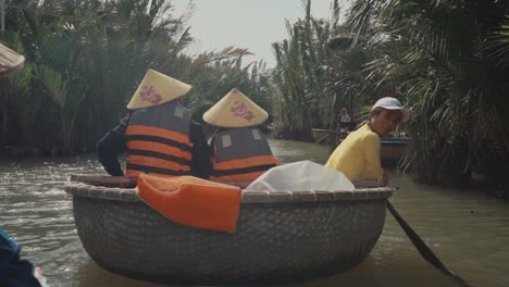 Erwachsene-Mit-Kegelhüten-Fahren-In-Einem-Runden-Korbboot-Den-Fluss-Hinunter