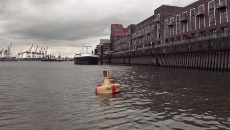 Drone-shot-of-a-marker-buoy-in-Hamburg-harbour-labelled-Restricted-Area-for-shipping-floating-on-the-water-of-the-River-Elbe-on-a-cloudy-day