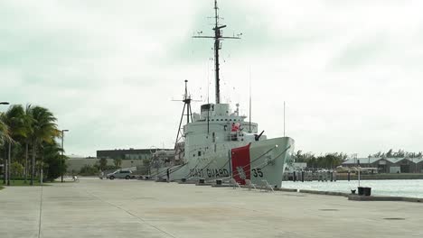 US-Coast-Guard-Ship-Docked-in-Key-West,-Florida-on-a-Cloudy-Day-Pan-Down-From-Sky