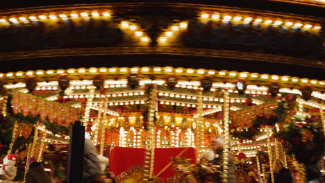 Vista-De-Cerca-De-Luces-Brillantes,-Adornos-Navideños-Y-Jinetes-Disfrutando-De-Un-Giro-En-Un-Carrusel-Mientras-Visitan-Una-Feria