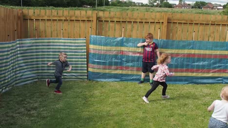 Grandparents-and-parents-playing-games-with-grandchildren-in-garden-during-summertime