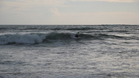 Hombre-Bodysurfing-Una-Pequeña-Ola-Frente-A-La-Costa-De-Bali,-Indonesia