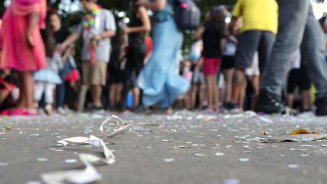 Straßenkarneval-Mit-Konfetti-Und-Papier-Auf-Dem-Boden,-Im-Hintergrund-Verschwommen-Eine-Gruppe-älterer-Und-Jüngerer-Menschen