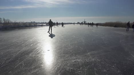 Gente-Patinando-Sobre-Hielo-En-Un-Canal-Congelado-Holandés-En-Invierno