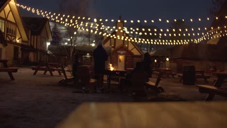 La-Familia-De-La-Estación-De-Esquí-Se-Relaja-Alrededor-De-Un-Acogedor-Fuego-Bajo-Las-Luces-De-Invierno.