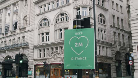 Lockdown-in-London,-close-up-slow-motion-pan-of-KEEP-TWO-METERS-DISTANCE-sign-on-empty-Piccadilly-streets,-during-the-Coronavirus-pandemic-2020