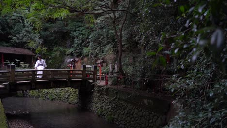 Revelación-Lenta-Del-Hombre-Con-Ropa-Típica-De-Kimono-Japonés-De-Pie-En-El-Puente-De-Un-Pequeño-Santuario-En-El-Bosque