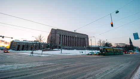 Timelapse-of-traffic-in-front-of-the-Parliament-house-of-Helsinki,-sunny-winter-evening,-in-Finland---Static,-time-lapse-view